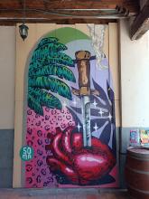 Street art: A sword or knife stuck in a heart (organ), next to possible a giant strawberry. Something undefined hanging from a ceiling.