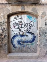 Street art: a worm like create with a human but square face and one arm.