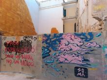 Street art: pink clouds on a wall, a construction site in the back