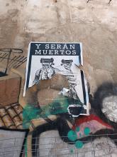 Street art: damaged piece of two dressed skeletons and the spanish text "y serán muertos" probably meaning "and they will be killed".