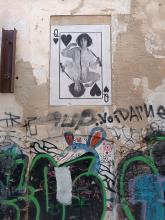 Street art: The queen card of a deck depciting a woman in a shirt with perhaps a loose tie around her neck