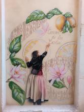 Street art: a girl trying to reach high hanging huge lemons.
