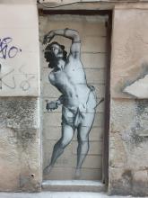 Street art: a barely dressed man in devout posture with a smartphone in his hand.